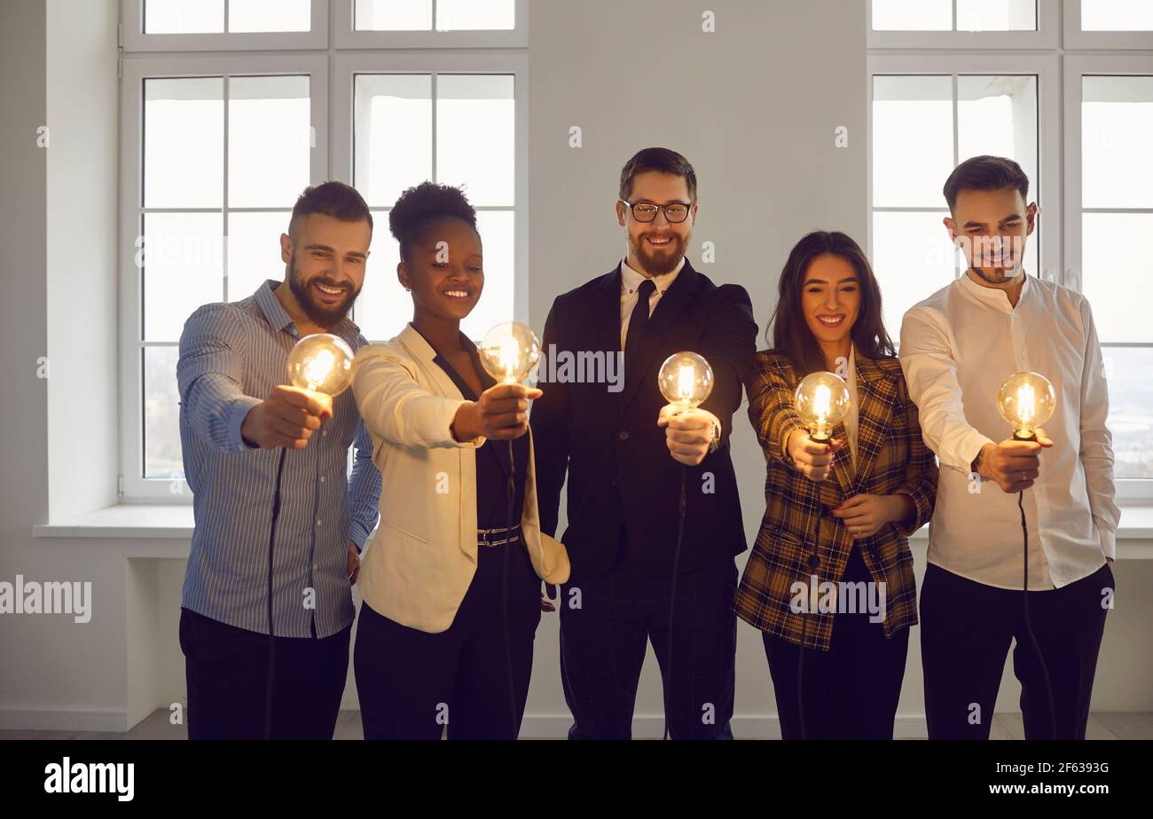 Groupe de personnes créatives souriantes et variées, dont les hommes d'affaires sont illuminés ampoules Banque D'Images