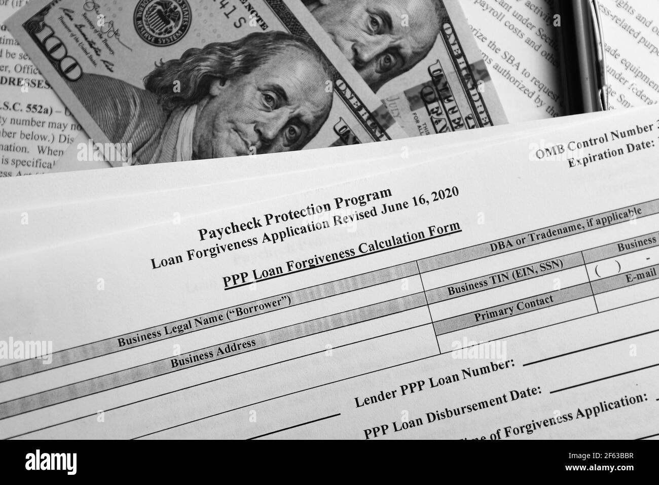photo sélective du programme de protection des chèques de paie formulaire de demande de remise de prêt révisé, sur un fond de billets en dollars et un stylo Banque D'Images