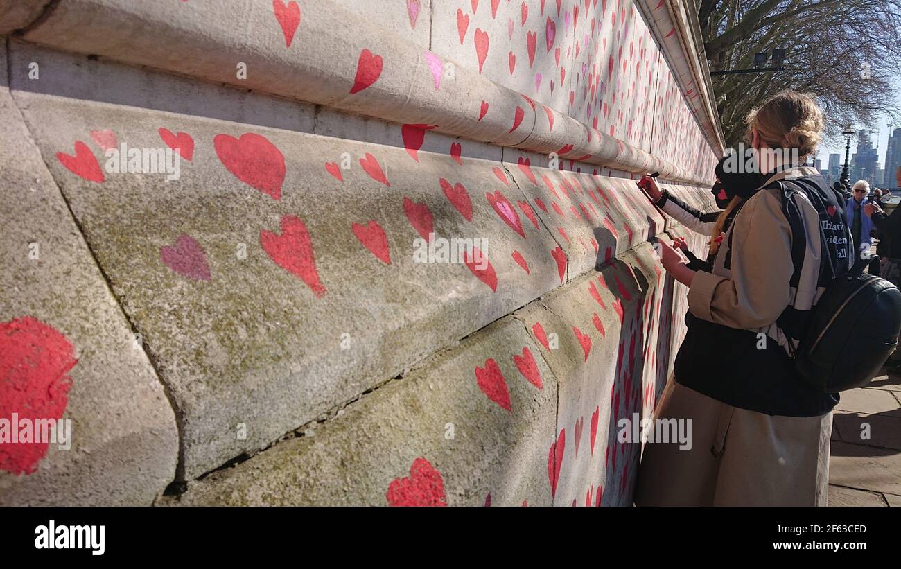 Londres, Royaume-Uni. 29 mars 2021. La famille et les amis endeuillés sont visités par Keir Starmer alors qu'ils peignent des coeurs sur le mur commémoratif Covid. Banque D'Images