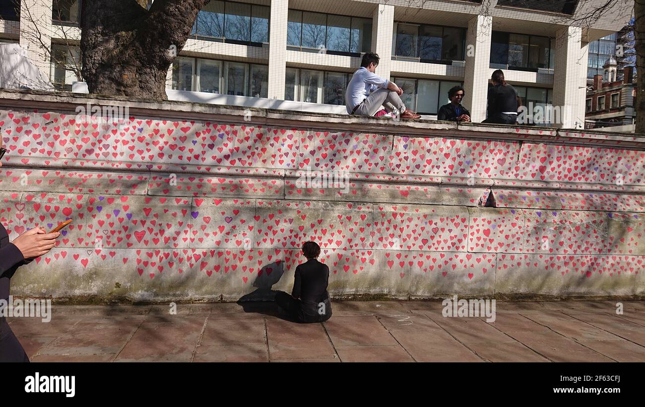 Londres, Royaume-Uni. 29 mars 2021. La famille et les amis endeuillés sont visités par Keir Starmer alors qu'ils peignent des coeurs sur le mur commémoratif Covid. Banque D'Images