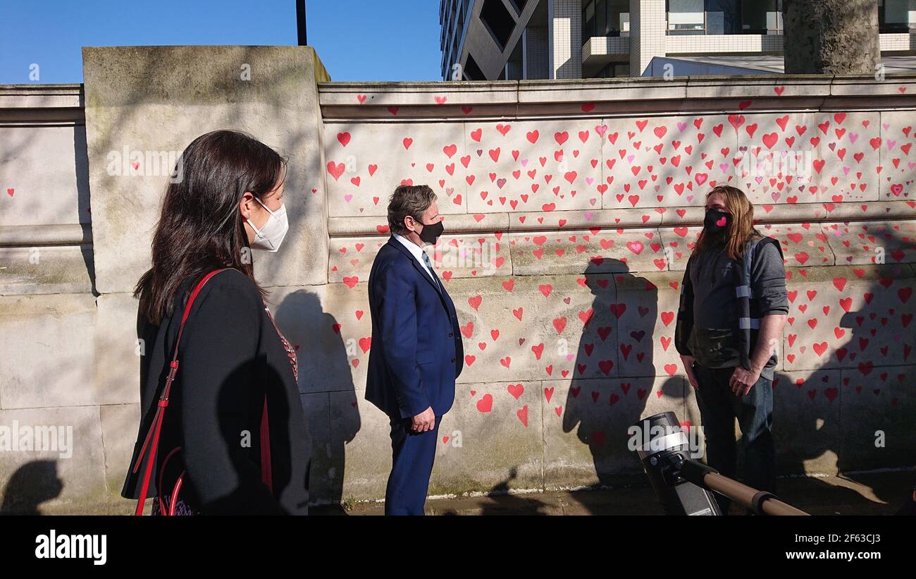 Londres, Royaume-Uni. 29 mars 2021. La famille et les amis endeuillés sont visités par Keir Starmer alors qu'ils peignent des coeurs sur le mur commémoratif Covid. Banque D'Images