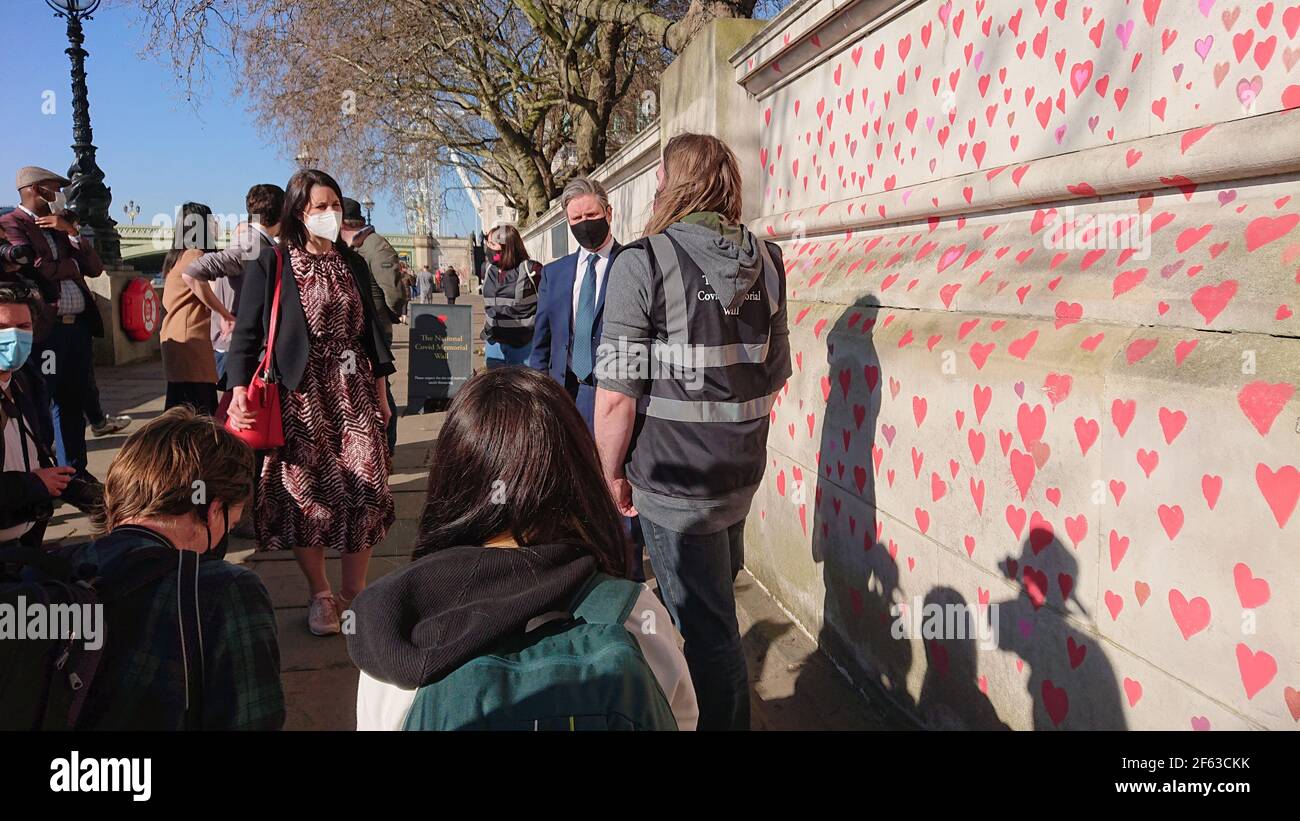 Londres, Royaume-Uni. 29 mars 2021. La famille et les amis endeuillés sont visités par Keir Starmer alors qu'ils peignent des coeurs sur le mur commémoratif Covid. Banque D'Images