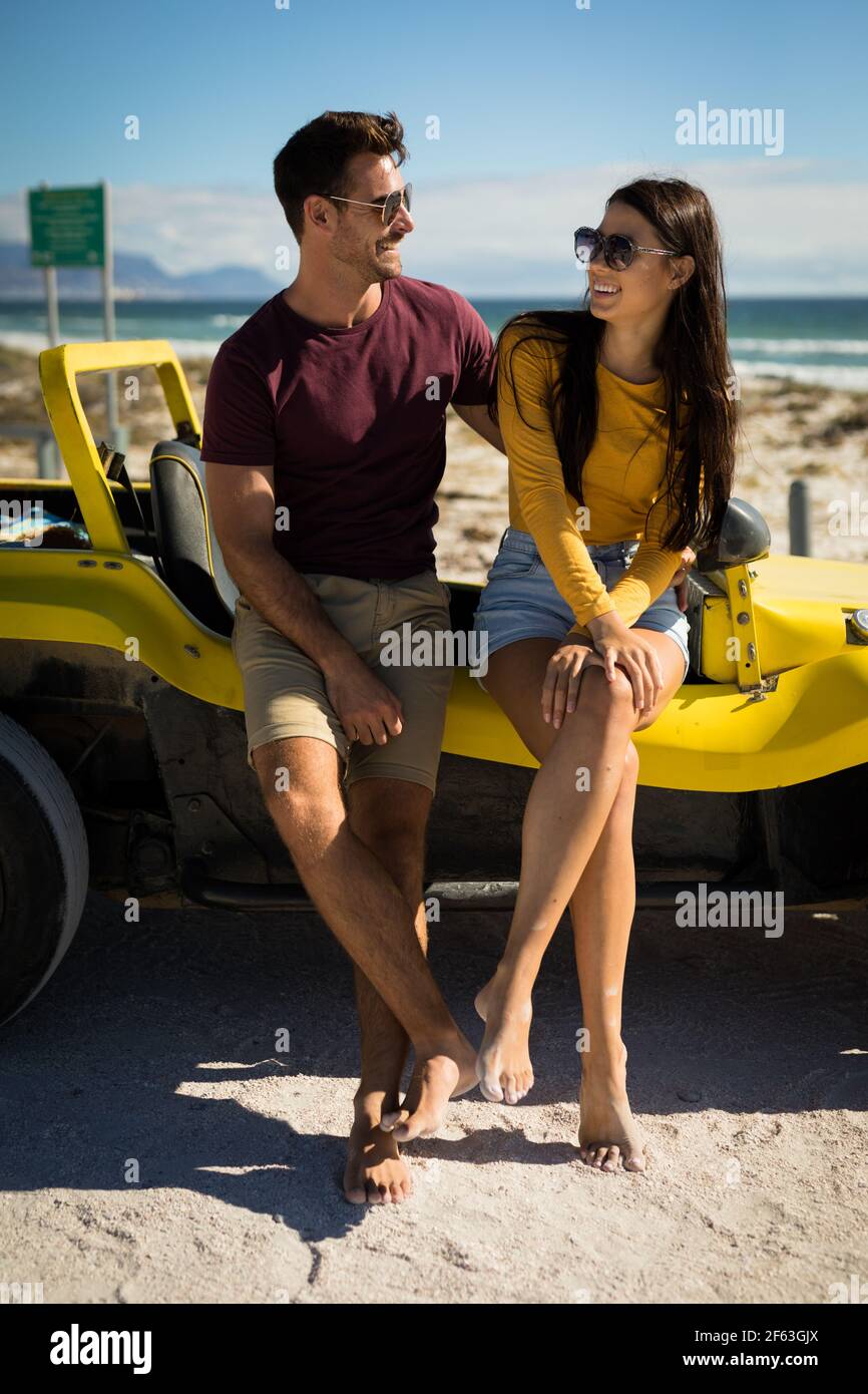 Heureux couple caucasien assis sur la plage buggy au bord de la mer s'embrasser Banque D'Images