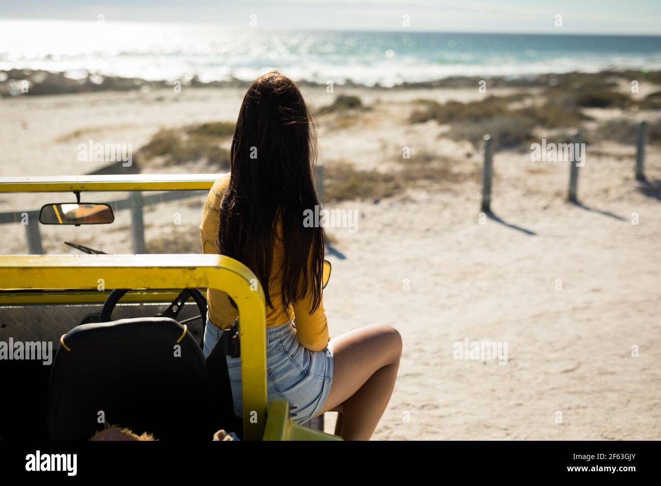 Femme caucasienne assise sur un buggy de plage en direction de la mer Banque D'Images