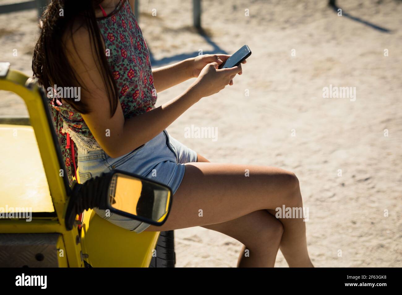 Section médiane de la femme caucasienne assise sur la plage buggy à côté de sea à l'aide d'un smartphone Banque D'Images