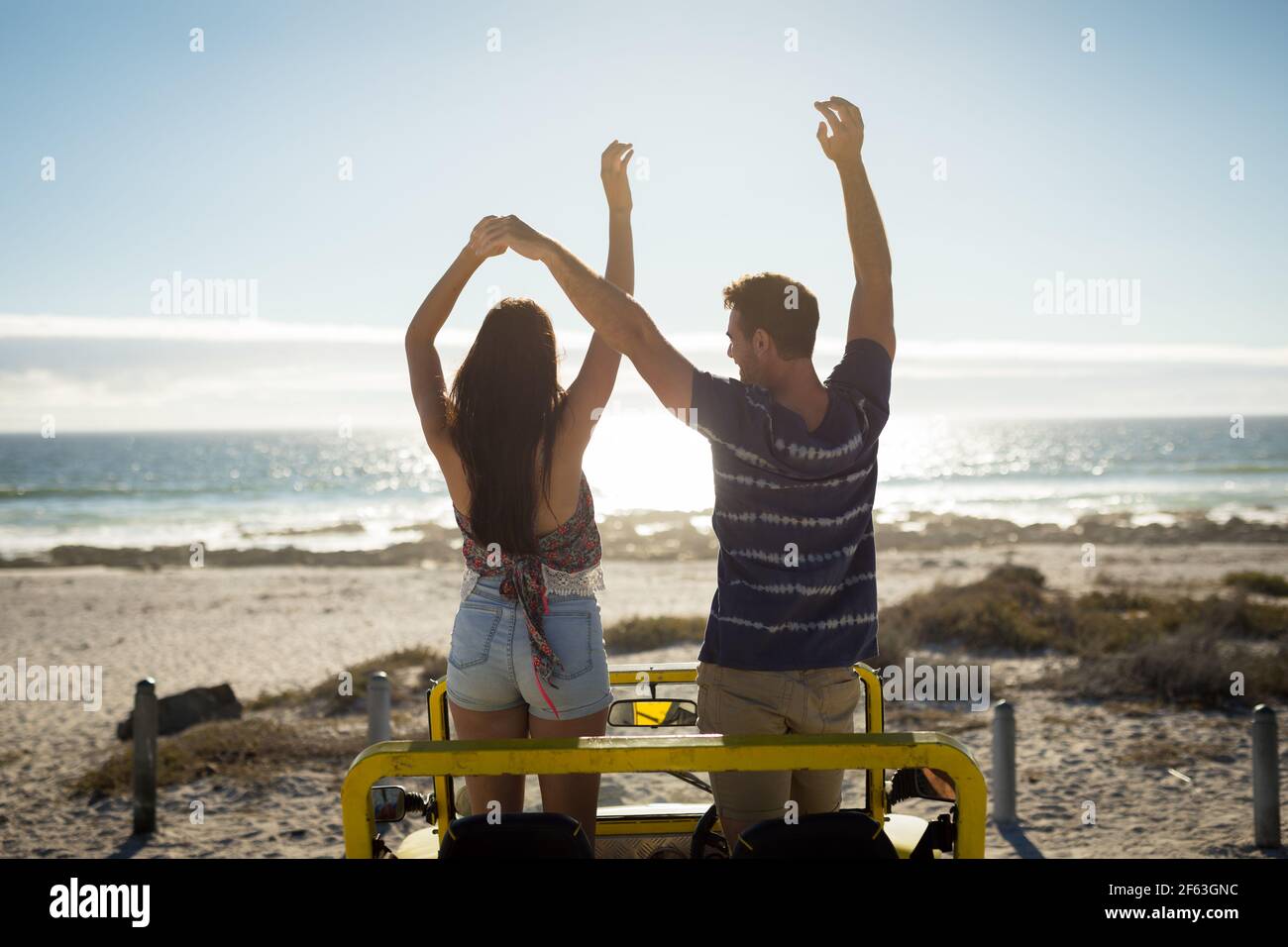 Couple de caucasiens heureux à la plage buggy au bord de la mer avec les mains vers le haut Banque D'Images