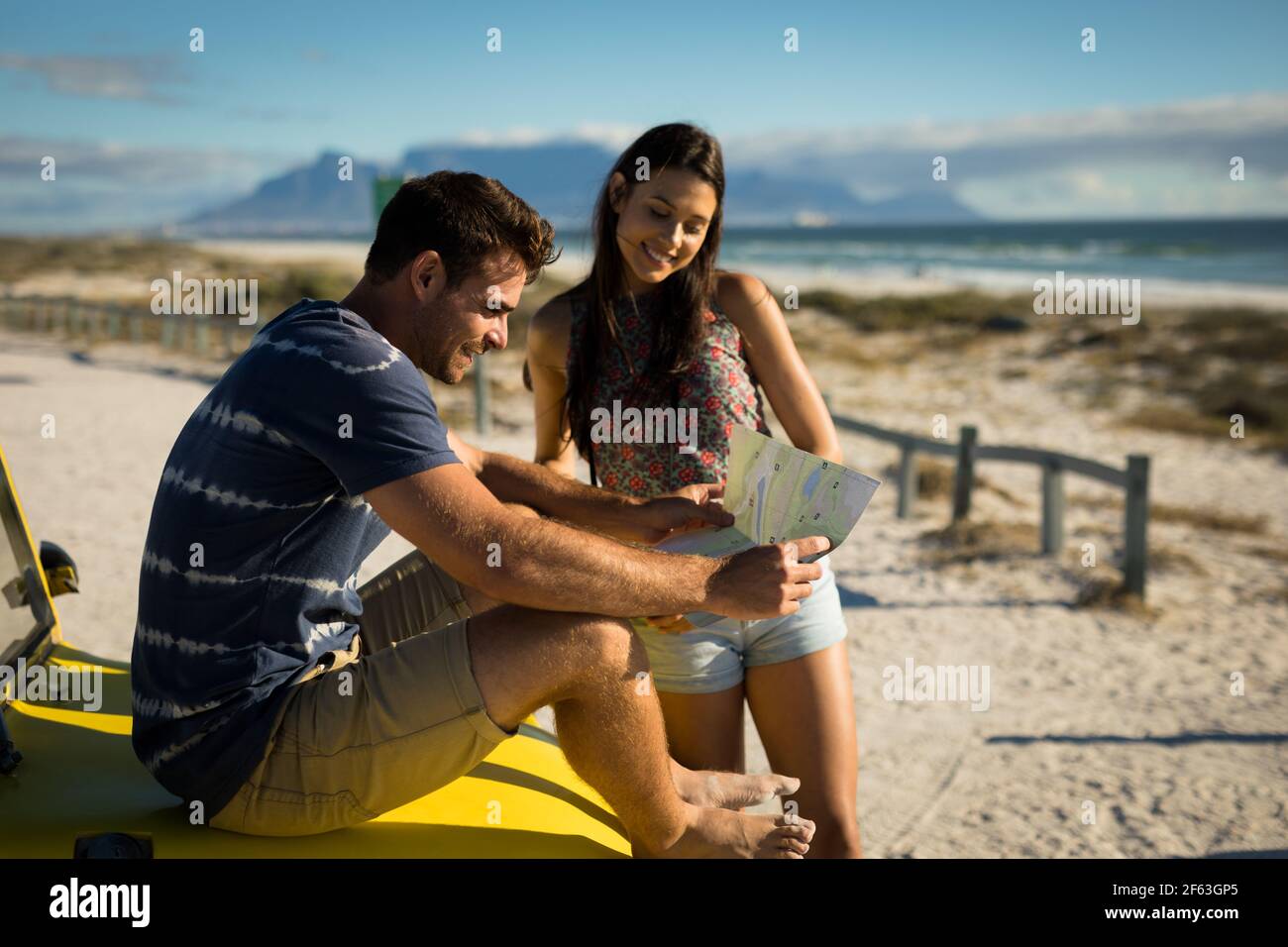 Heureux couple caucasien assis sur la plage buggy au bord de la mer vérification de la carte Banque D'Images