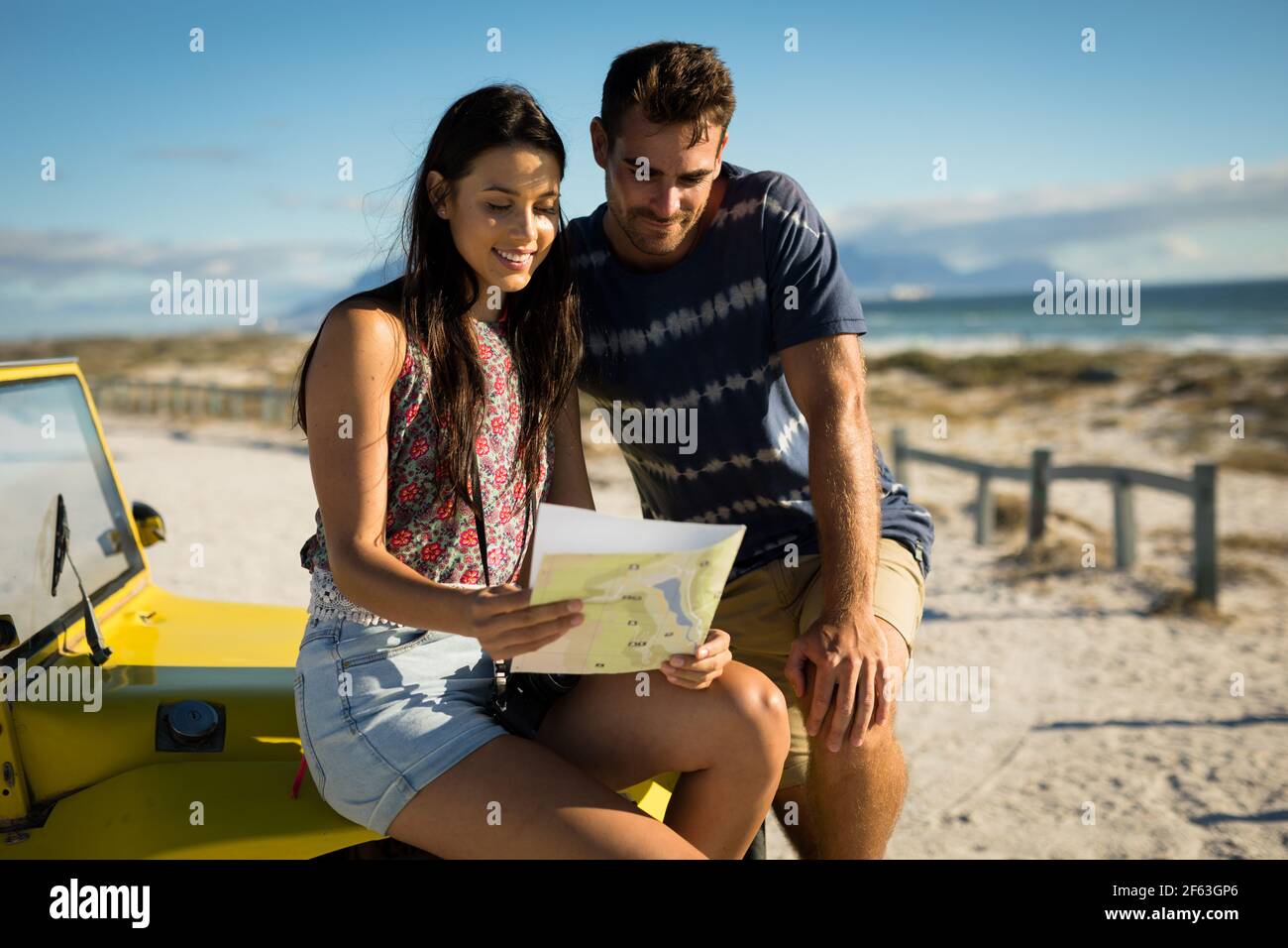 Heureux couple caucasien assis sur la plage buggy au bord de la mer lecture de la feuille de route Banque D'Images