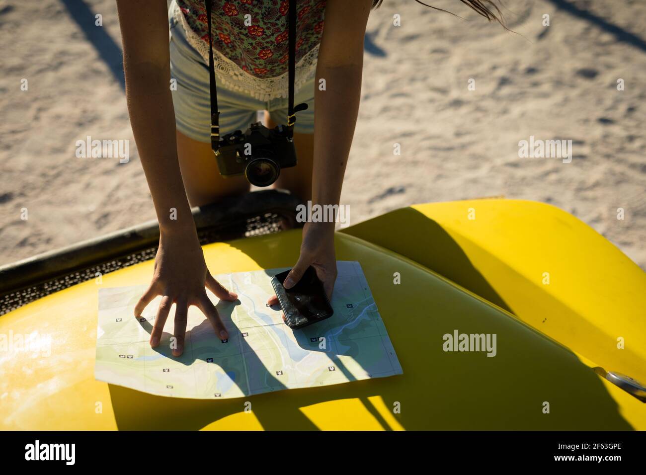 Section médiane de la femme caucasienne lisant la feuille de route sur la plage buggy par la mer Banque D'Images