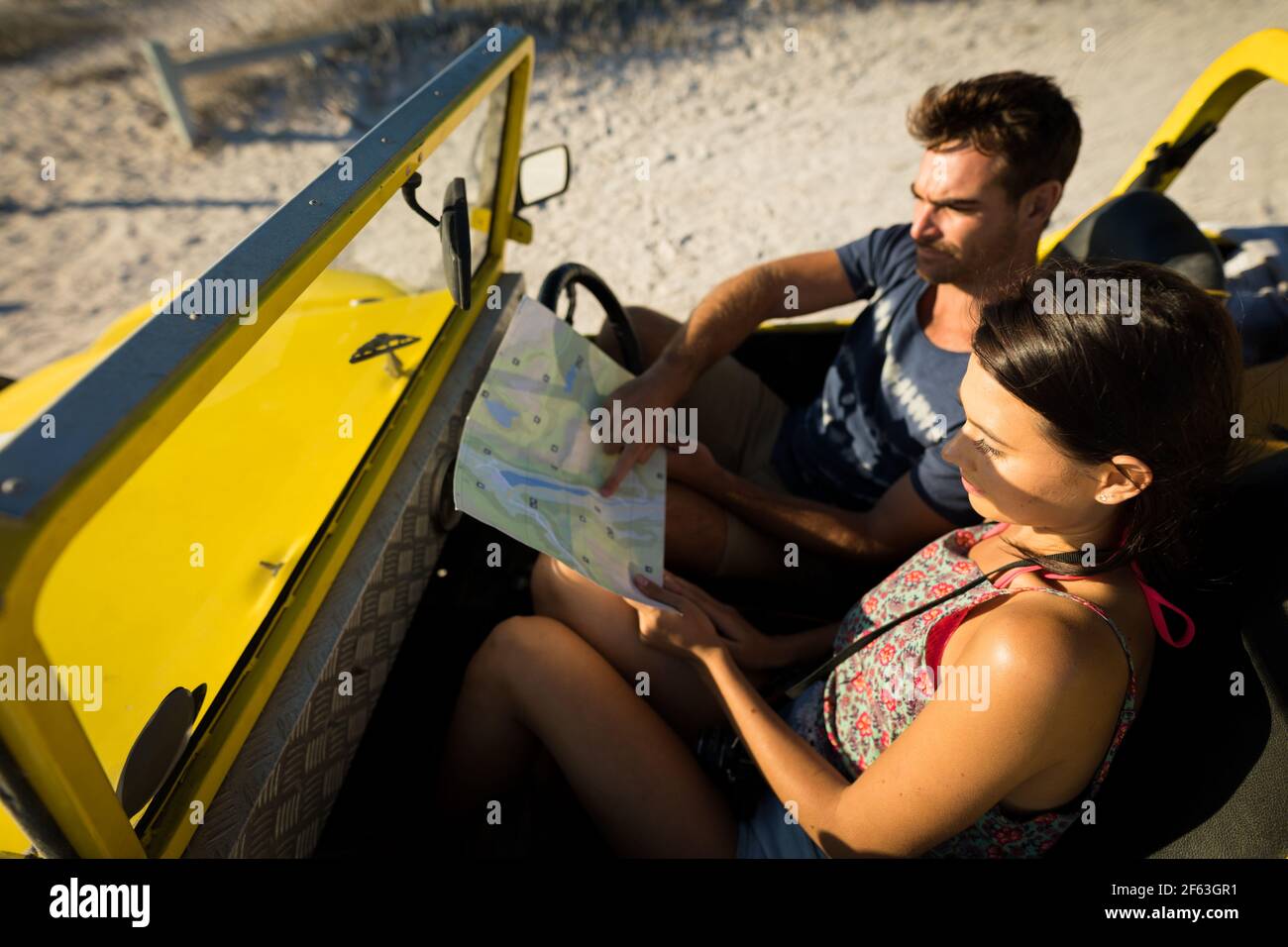 Heureux couple caucasien assis dans la plage buggy au bord de la mer lecture de la feuille de route Banque D'Images