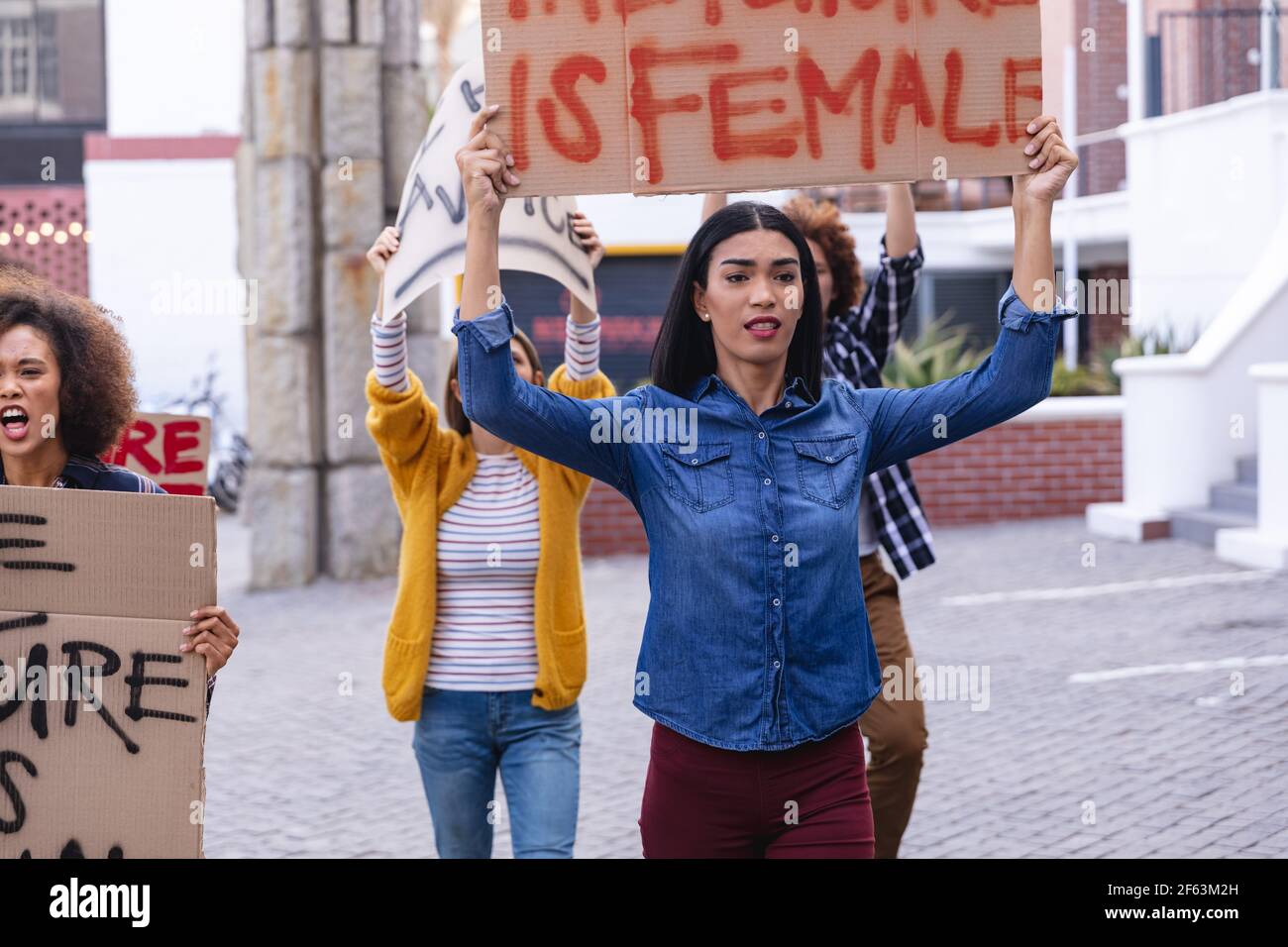 Une protestation féminine de race mixte a lieu le mois de mars, dans le cadre d'une manifestation maison signe au-dessus de sa tête Banque D'Images