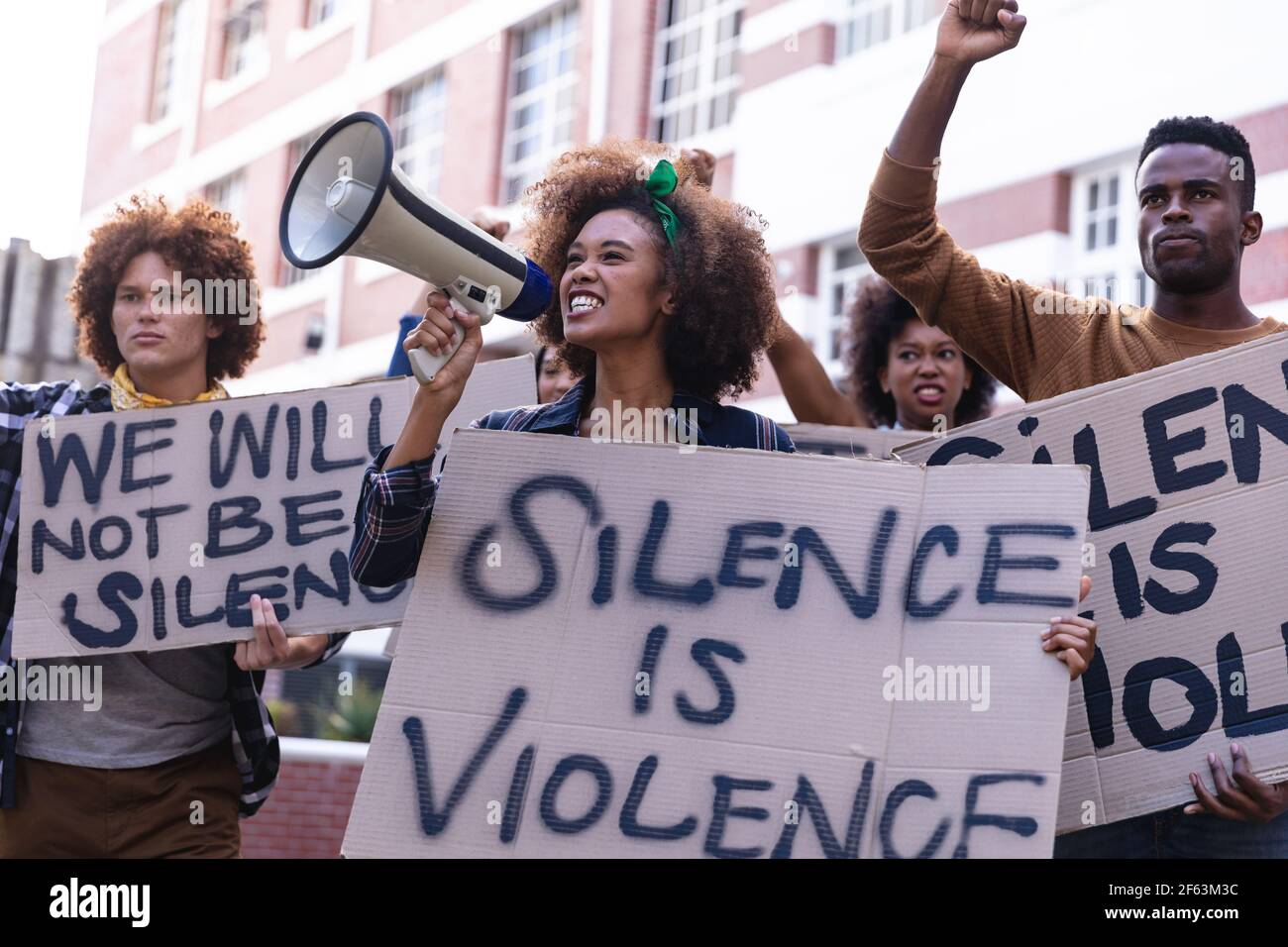 Divers manifestants masculins et féminins, le mois de mars, ont fait des signes de protestation, levant des poings et utilisant le mégaphone Banque D'Images