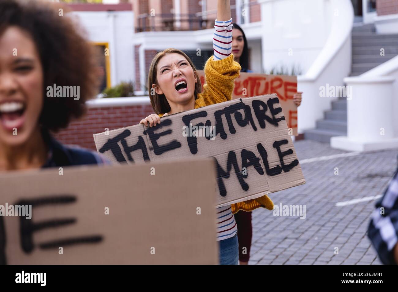 Une manifestante caucasienne tient en mars un panneau de protestation fait maison et crier avec le bras relevé Banque D'Images
