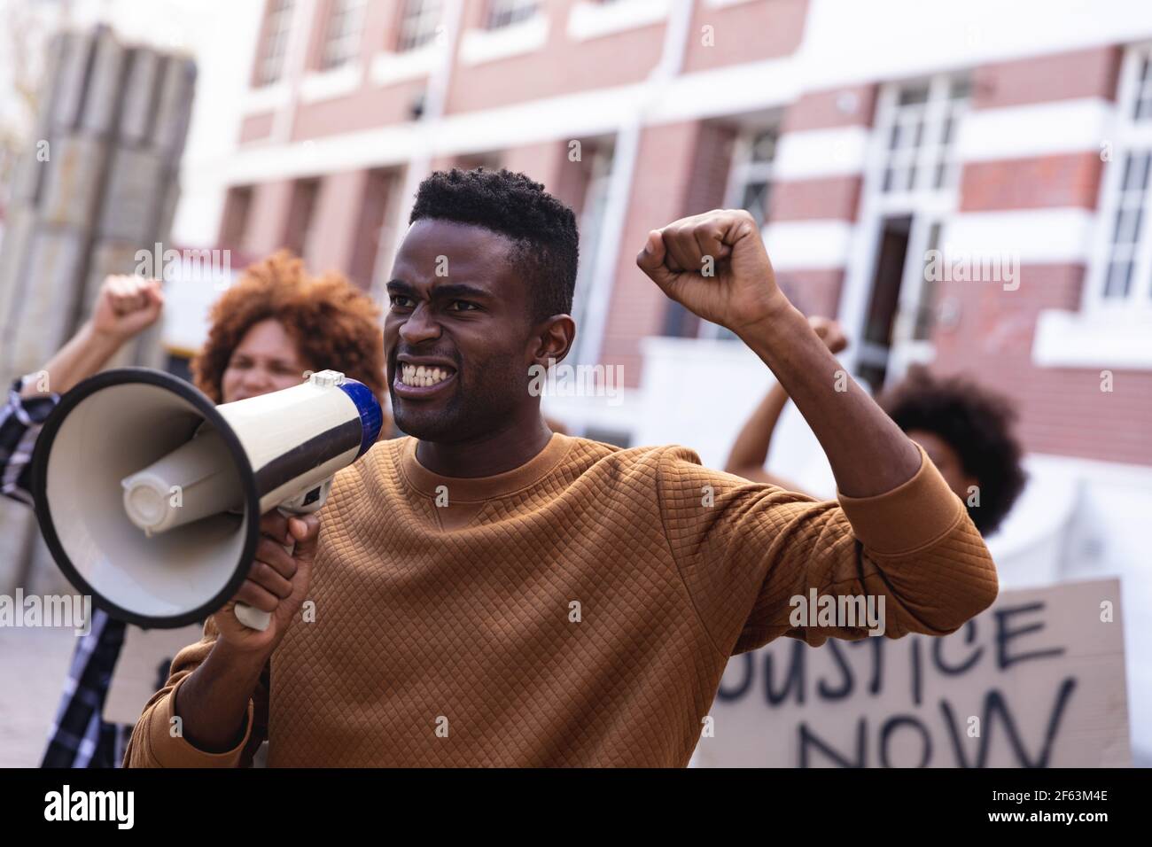 Homme afro-américain utilisant le mégaphone avec des manifestants lors de la tenue du mois de mars des signes et des poings Banque D'Images