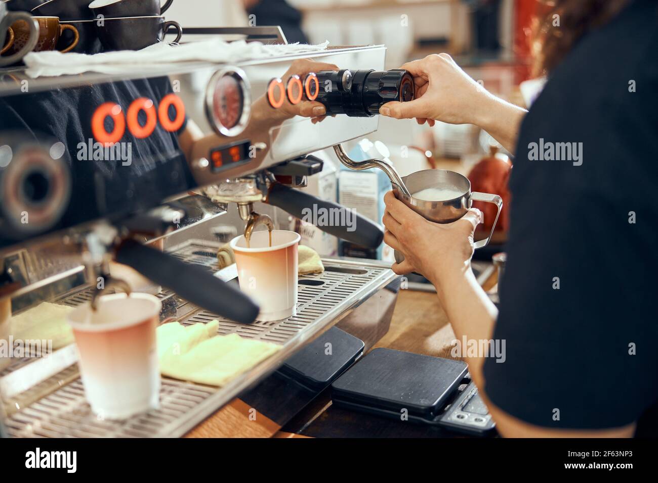 Image du barista féminin utilisant une machine à café pour faire cuire le lait dans le café Banque D'Images