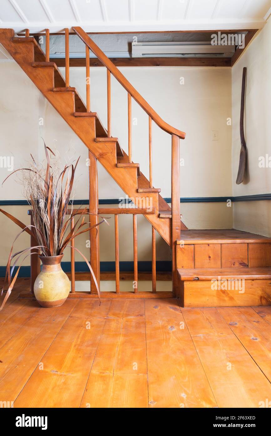 Escalier en pin jaune huilé et vase en céramique avec séché Tiges dans la salle de séjour à l'intérieur d'un vieux cottage Canadiana de 1825 style fieldstone maison Banque D'Images