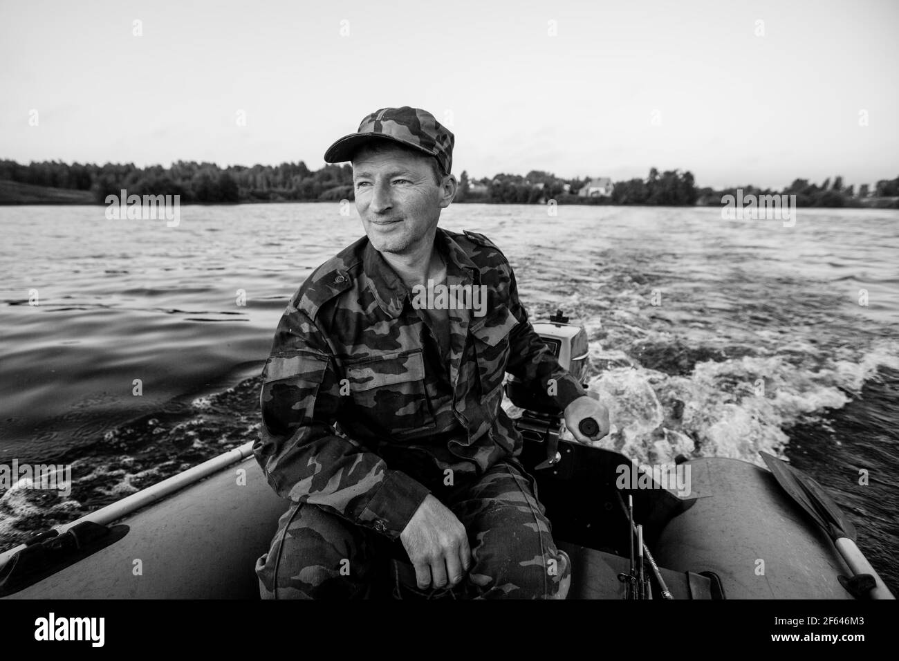 Un homme sur un bateau à moteur en caoutchouc flotte sur le lac. Photo en noir et blanc. Banque D'Images