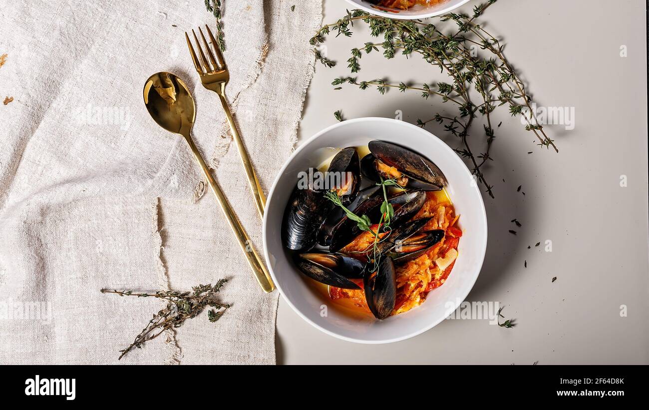 Bannière alimentaire. Une portion de moules avec des légumes dans un bol blanc sur fond clair. Fruits de mer délicieux et sains. Mollusques et crustacés. Vue de dessus Banque D'Images