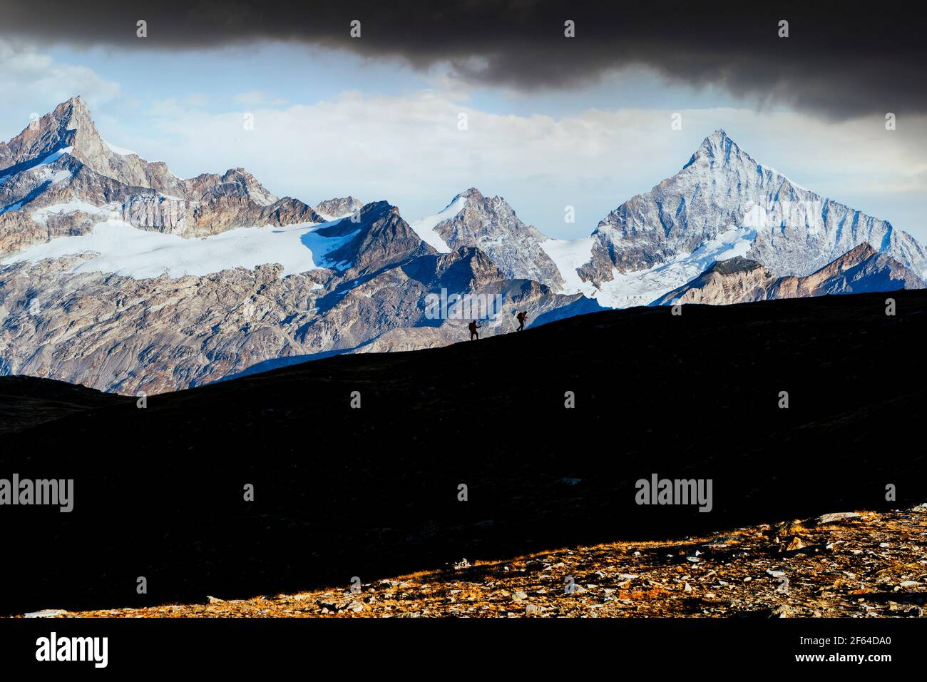 Randonneurs avec sac à dos marchant sur la crête de montagne avec Weisshorn en arrière-plan, canton du Valais, Suisse Banque D'Images