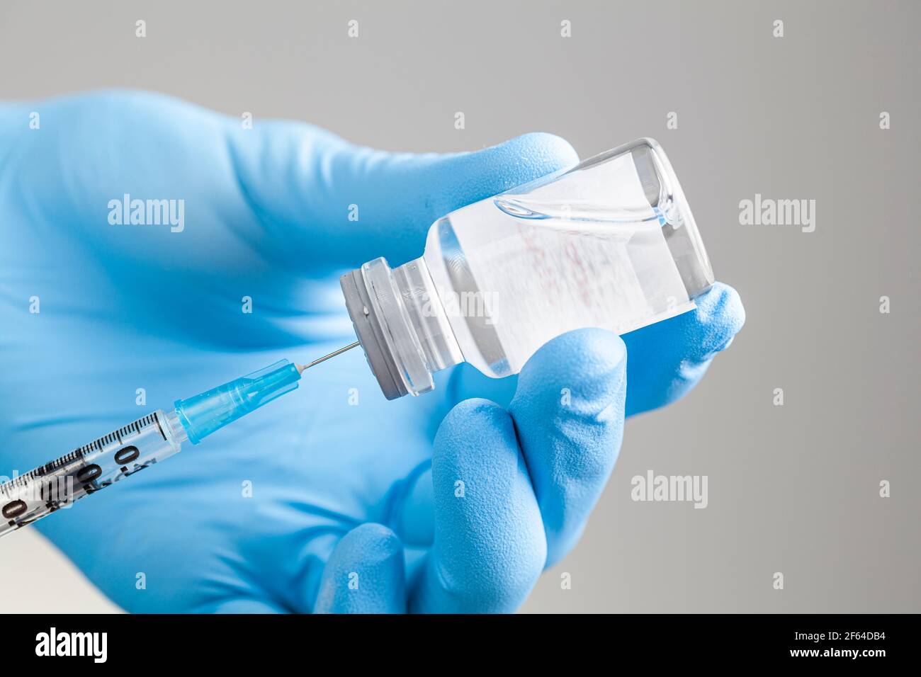 Gros plan image de concept isolée pour un professionnel de la santé qui aspire un médicament liquide ou un vaccin dans une seringue à partir d'un flacon en verre avec bouchon d'aspiration. Banque D'Images