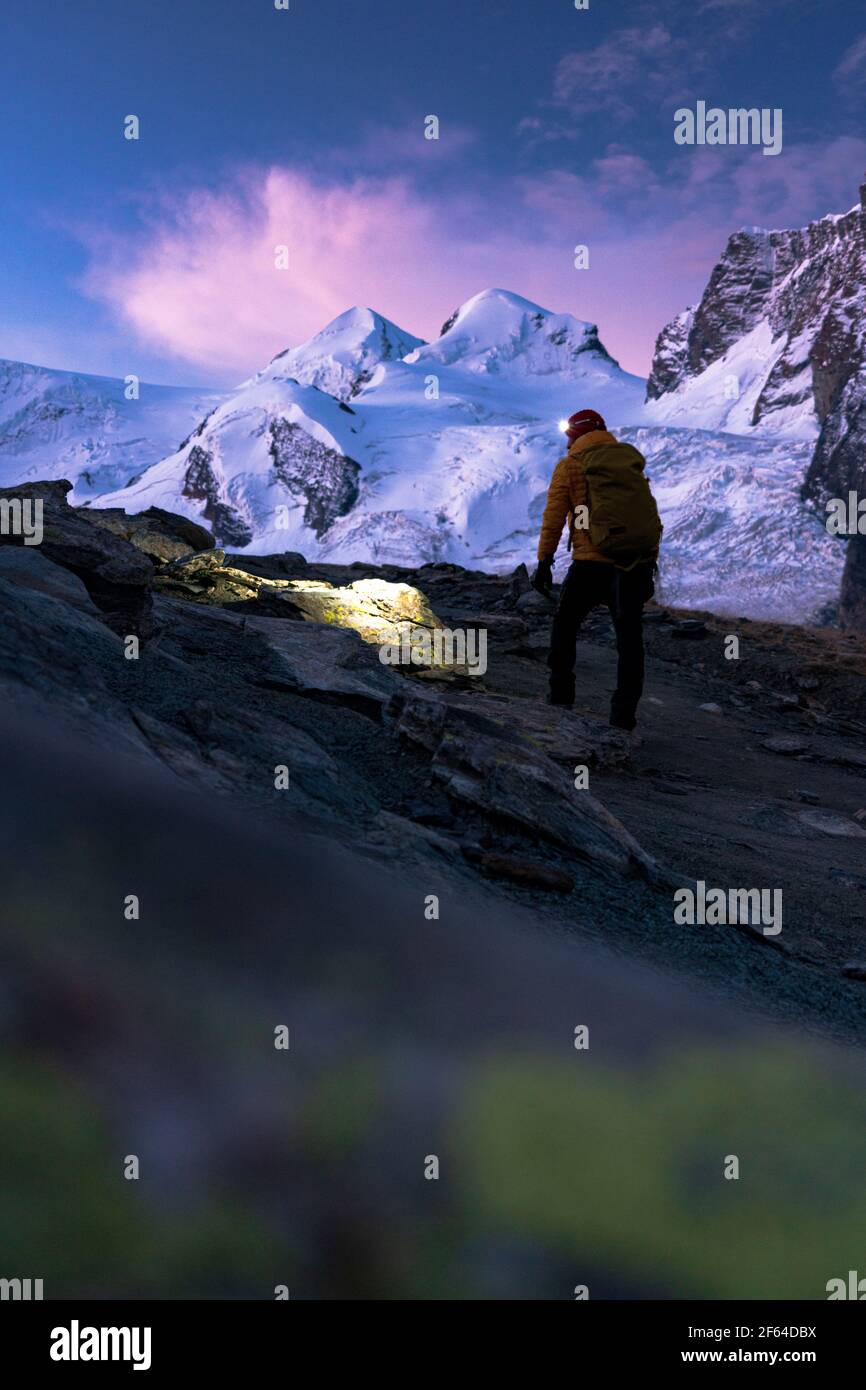 Mountaineer avec lampe frontale en admirant les sommets enneigés de Castor et Pollux à l'aube, Zermatt, canton du Valais, Suisse Banque D'Images