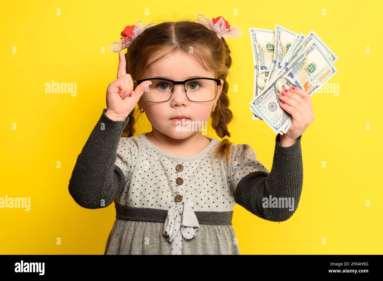 L'argent et les enfants sur le fond, une fille riche avec des verres tenant une grande somme d'argent. Nouveau Banque D'Images