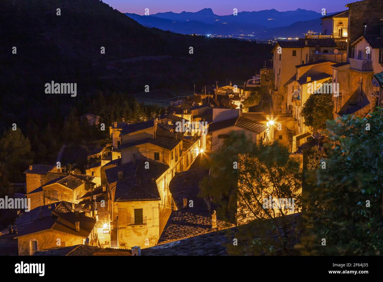 Panorama en soirée d'un village dans les montagnes illuminé par la lumière artificielle. En arrière-plan, la chaîne de montagnes Gran Sasso. Pettorano, Abruzzes Banque D'Images