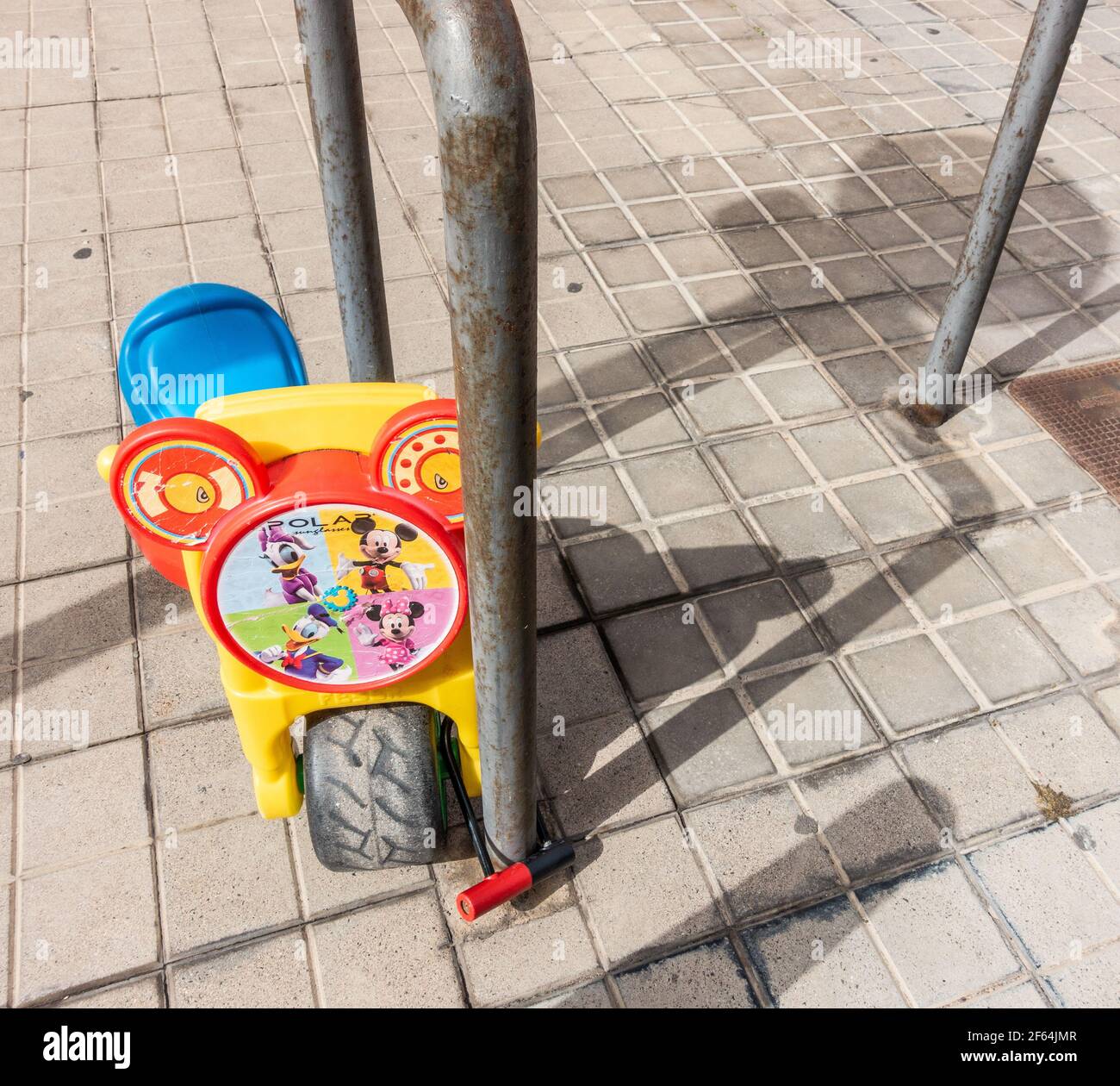 Vélo en plastique pour enfants verrouillé avec un cadenas en U pour service intensif poteau de parc à vélo à l'extérieur de l'école junior Banque D'Images