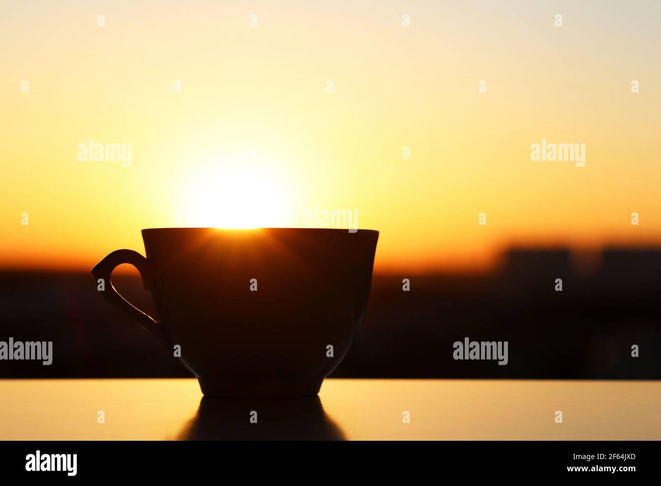 Silhouette de tasse de café sur fond de lever de soleil, départ frais le matin. Atmosphère chaleureuse, vue sur la ville depuis la fenêtre Banque D'Images