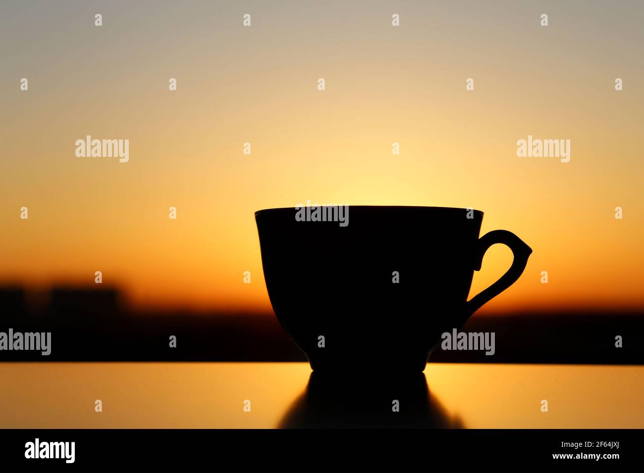 Silhouette de tasse de café sur fond de lever de soleil, départ frais le matin. Atmosphère chaleureuse, vue sur la ville depuis la fenêtre Banque D'Images