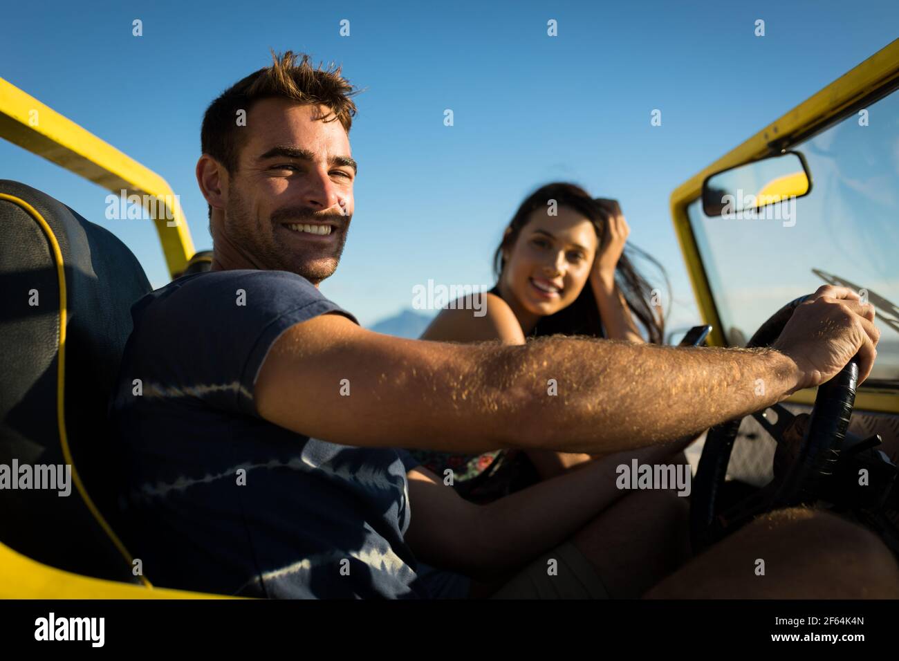 Heureux couple caucasien assis dans la plage buggy au bord de la mer regarder l'appareil photo Banque D'Images