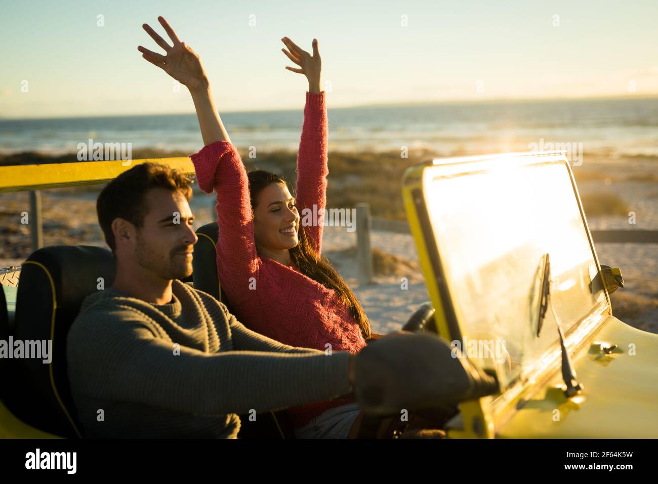 Heureux couple caucasien assis dans la plage buggy au bord de la mer au coucher du soleil Banque D'Images
