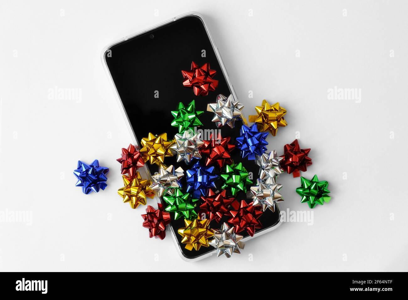 Smartphone avec noeuds cadeau de couleur sur fond blanc - concept de cadeaux et d'achats en ligne Banque D'Images