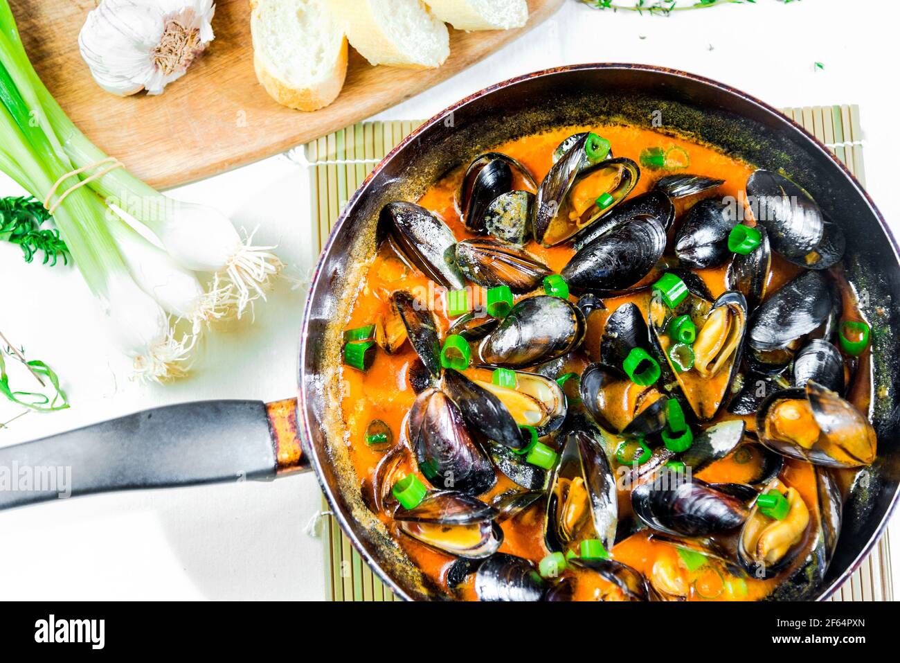 Délicieux moules de fruits de mer avec sauce rouge et oignons verts une casserole Banque D'Images