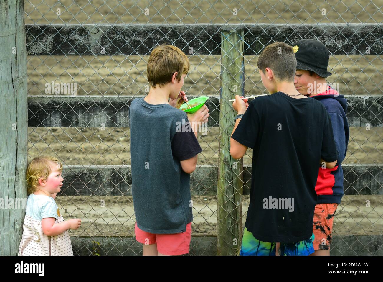 Photo de rue: Trois garçons appréciant la glace de l'eau un jour chaud d'été, et une petite fille les regardant sérieusement et probablement avec envie Banque D'Images