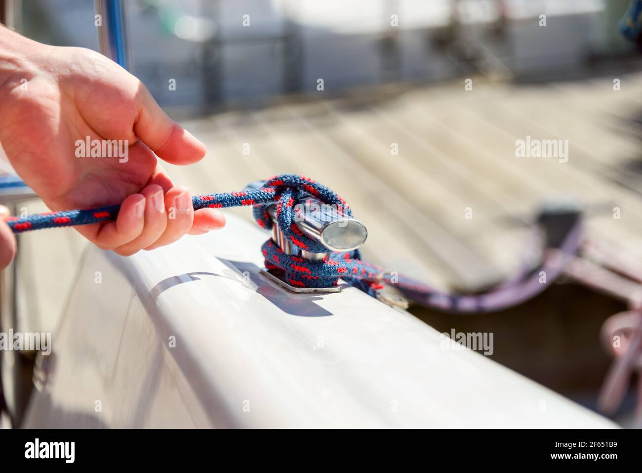 Homme main avec corde de bateau, yachtsman nouant le noeud de mer. Main humaine sur un bateau à voile ou un yacht noué, vue rapprochée Banque D'Images