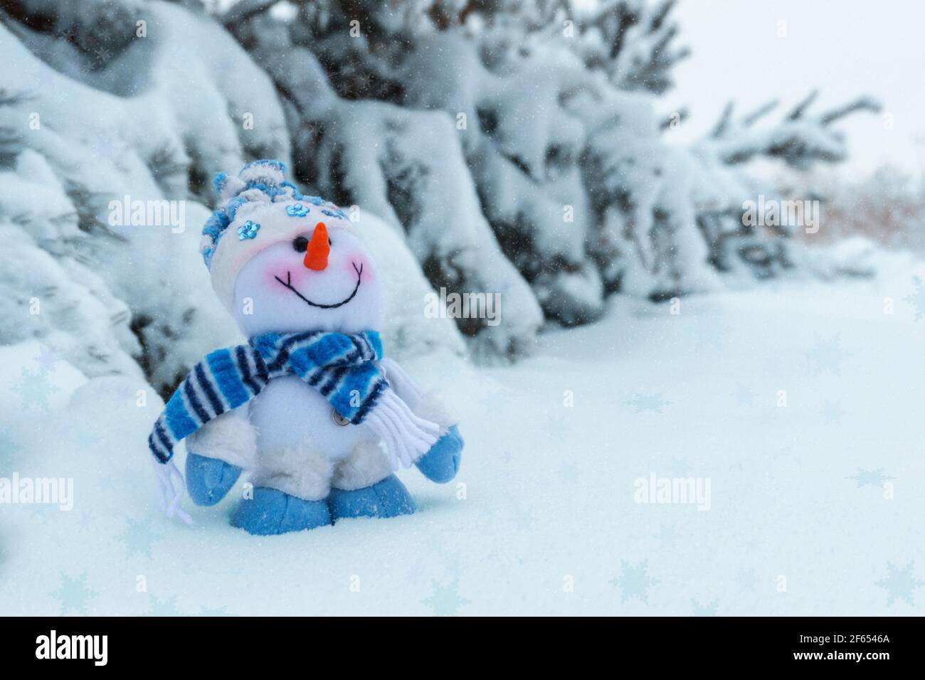 bonhomme de neige joyeux jouet dans la forêt d'hiver en arrière-plan d'arbres enneigés Banque D'Images