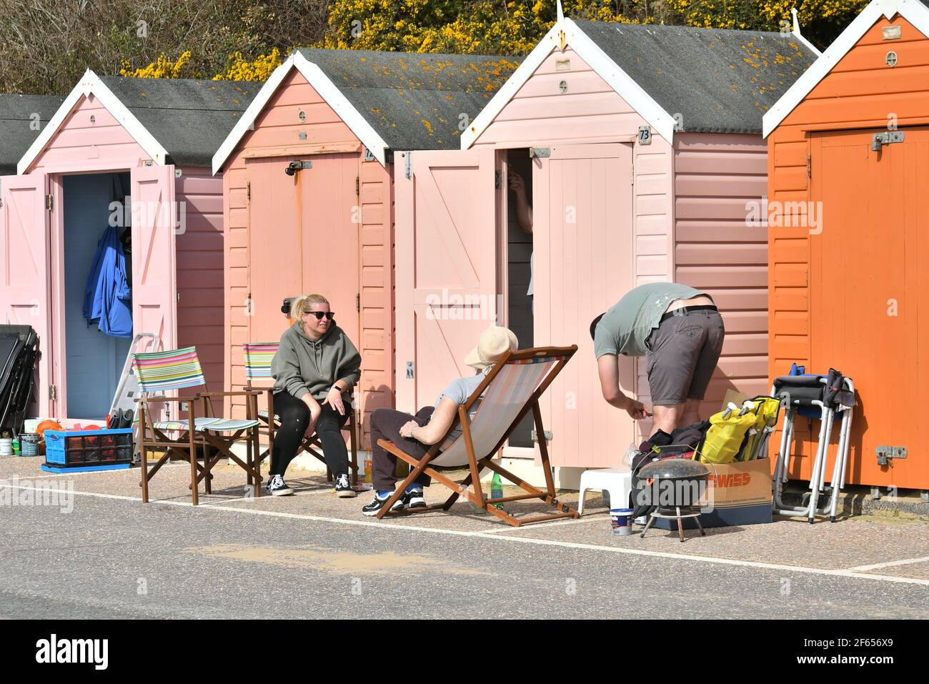 Bournemouth, Dorset, Royaume-Uni, 30th mars 2021, Météo. Une vague de chaleur du début du printemps. Les personnes avec des transats s'installer pour la journée à l'extérieur des cabines de plage sur la promenade. Banque D'Images