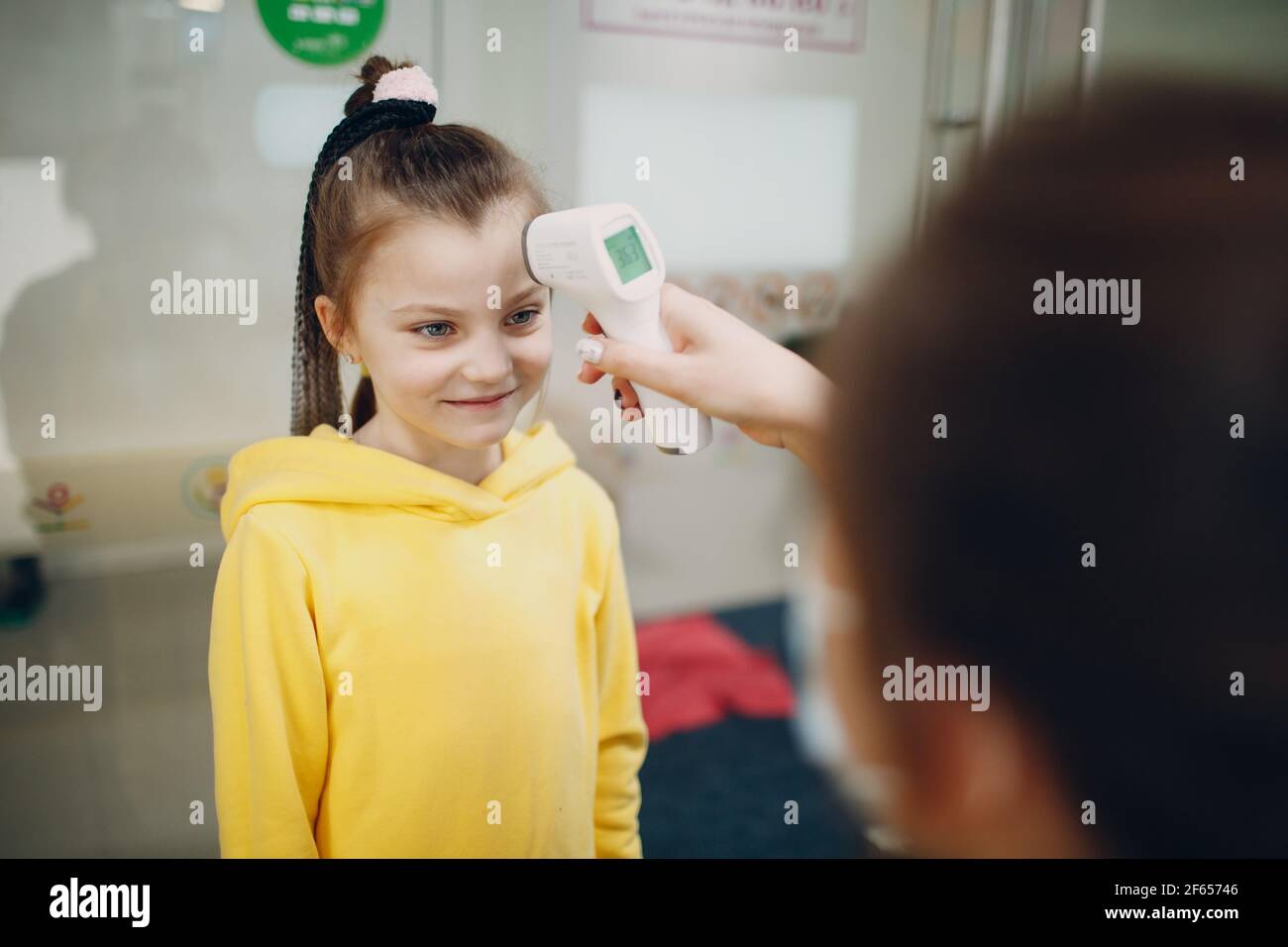 Mesure de la température de la tête de l'enfant par thermomètre laser à l'école maternelle Banque D'Images