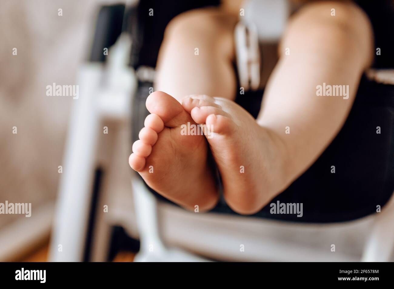 Les petits pieds de bébé sur la chaise haute, le petit enfant assis sur la chaise Banque D'Images