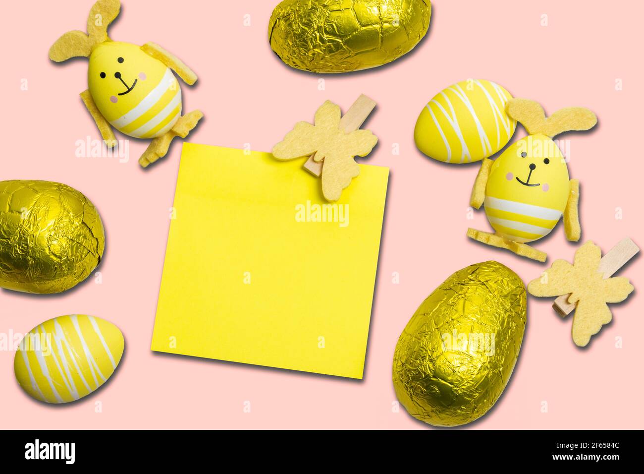 Œufs de Pâques, décorations et note adhésive jaune sur fond rose Banque D'Images