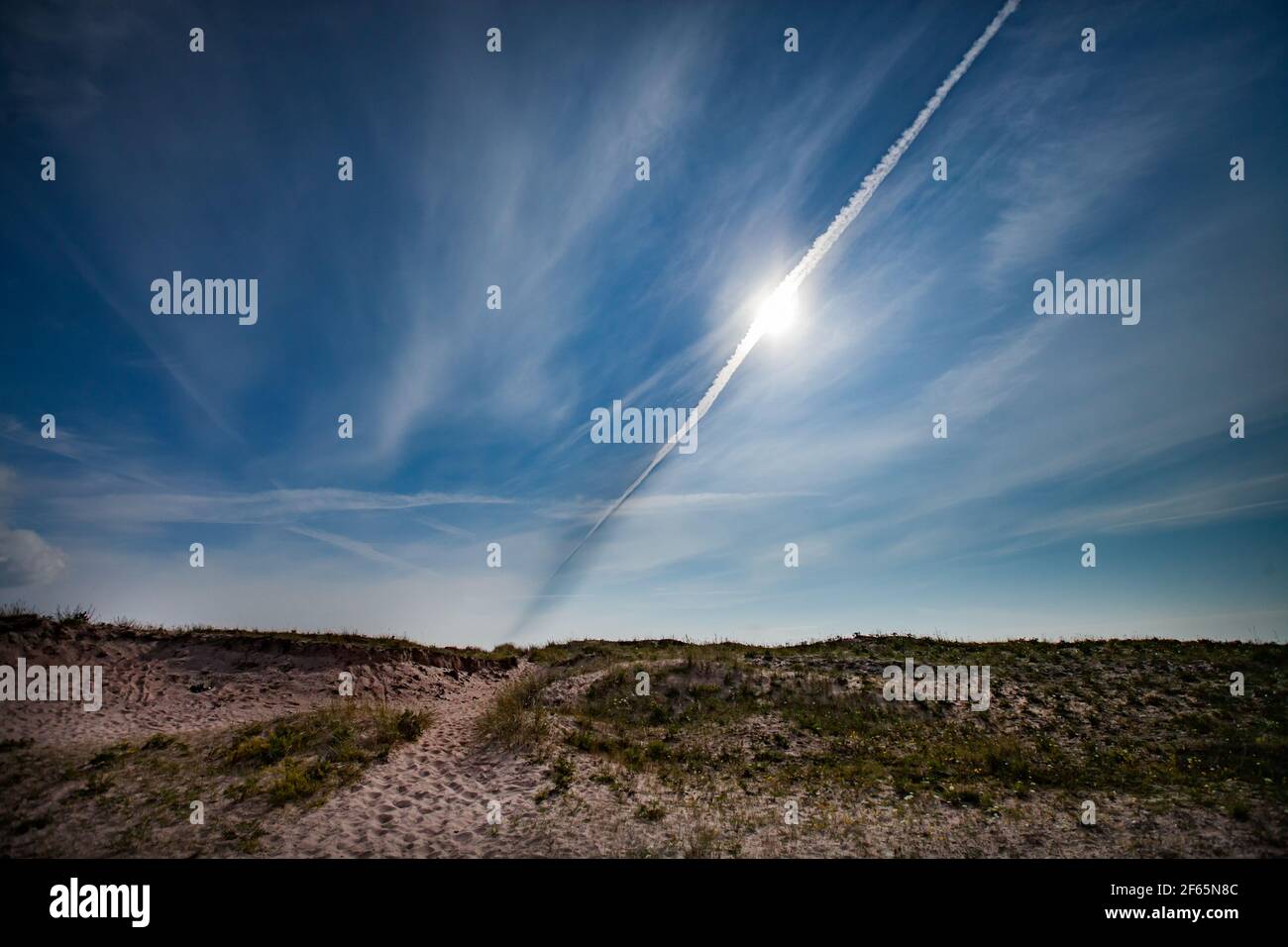 Dunes de sable sur ciel bleu avec soleil et traces de jet en arrière-plan. Estonie, Saarema, réserve naturelle de Harilaid. Banque D'Images