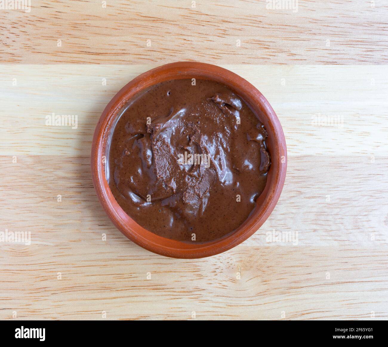 Vue de dessus d'un bol de beurre de noisette d'amande au chocolat sur une table en bois éclairée par un éclairage naturel. Banque D'Images