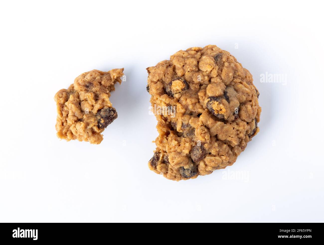 Vue en hauteur d'un biscuit au raisin de flocons d'avoine maison cassé en deux morceaux sur une assiette blanche éclairée par la lumière naturelle. Banque D'Images