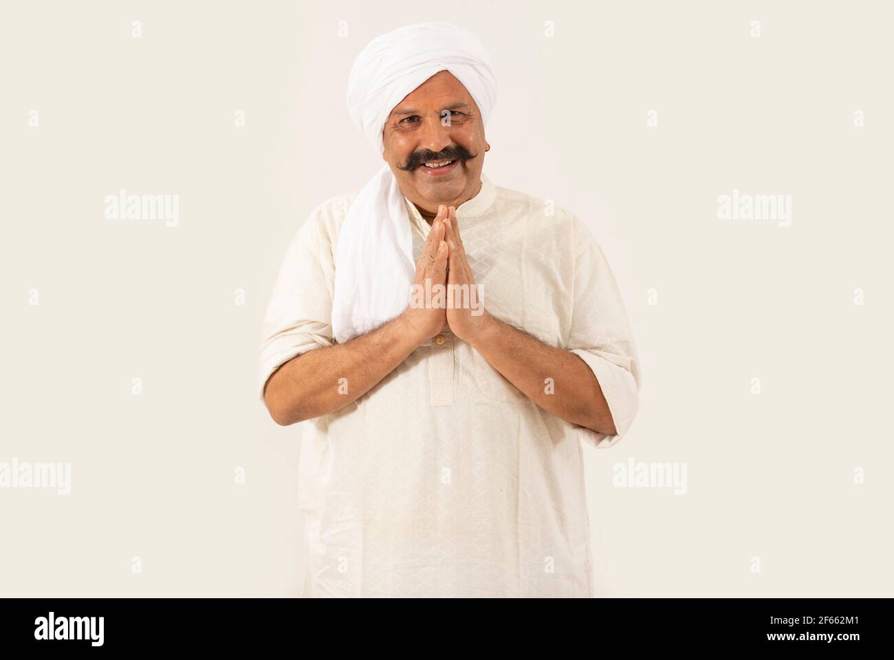 UN VILLAGEOIS EN TRAIN DE TOURNIER SOURIANT À L'APPAREIL PHOTO ET SALUANT AVEC PLIÉ MAINS Banque D'Images