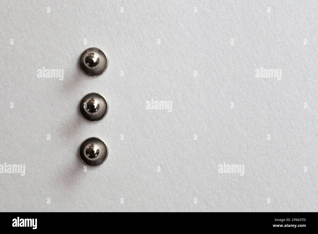 minimalisme gros plan trois passe-fils, rivet, bouton-pression sur fond  papier argenté Photo Stock - Alamy