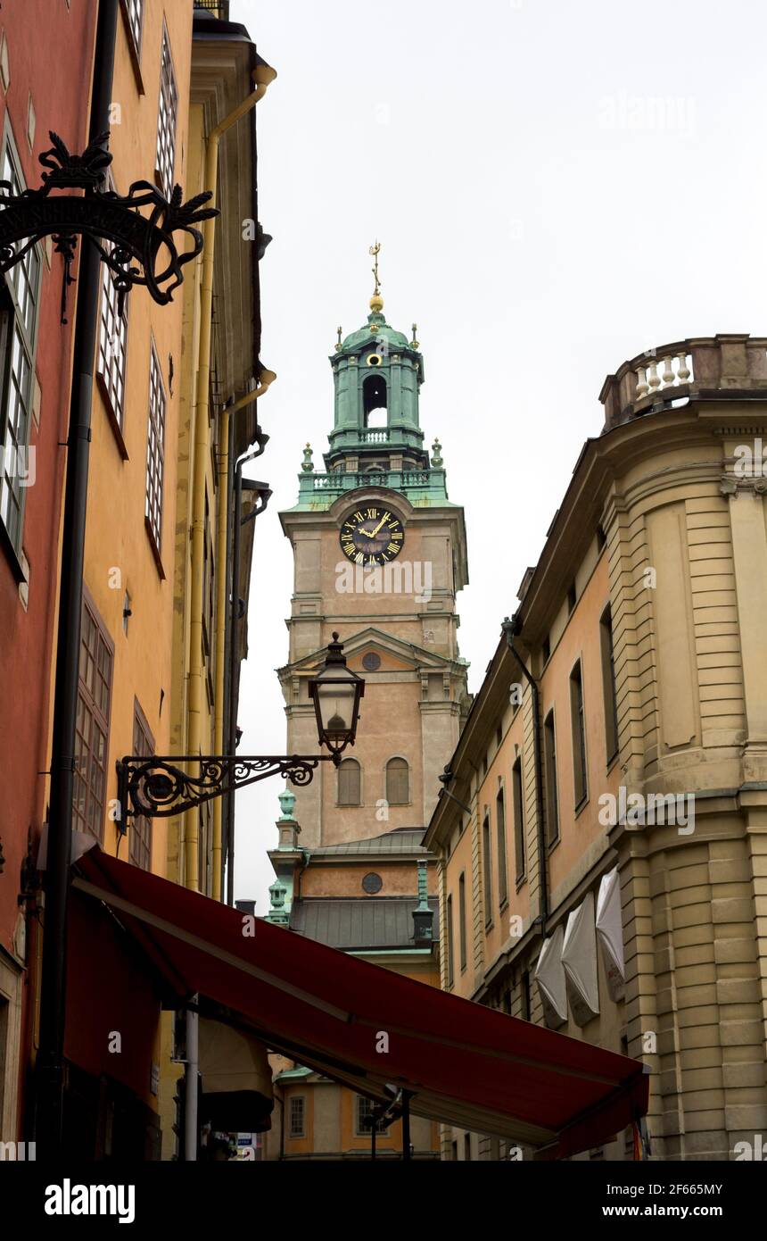 Une rue étroite à Gamla Stan, Stockholm, Suède, avec des bâtiments colorés de chaque côté et la tour de Storkyrkan visible au-delà. Banque D'Images