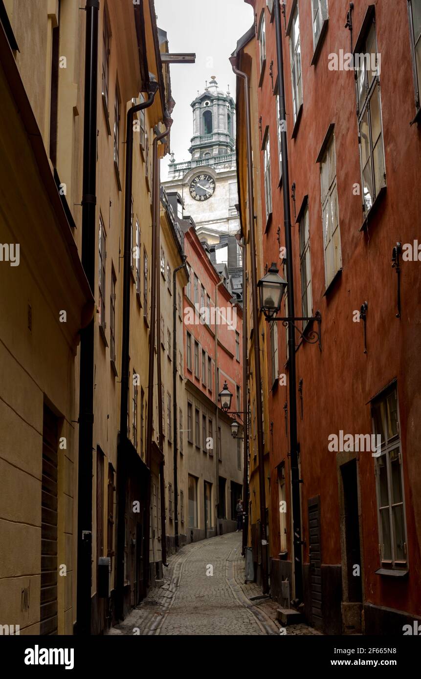 Une petite rue sinueuse à Gamla Stan, Stockholm, Suède, avec des bâtiments colorés de chaque côté et la tour de Storkyrkan visible au-delà. Banque D'Images
