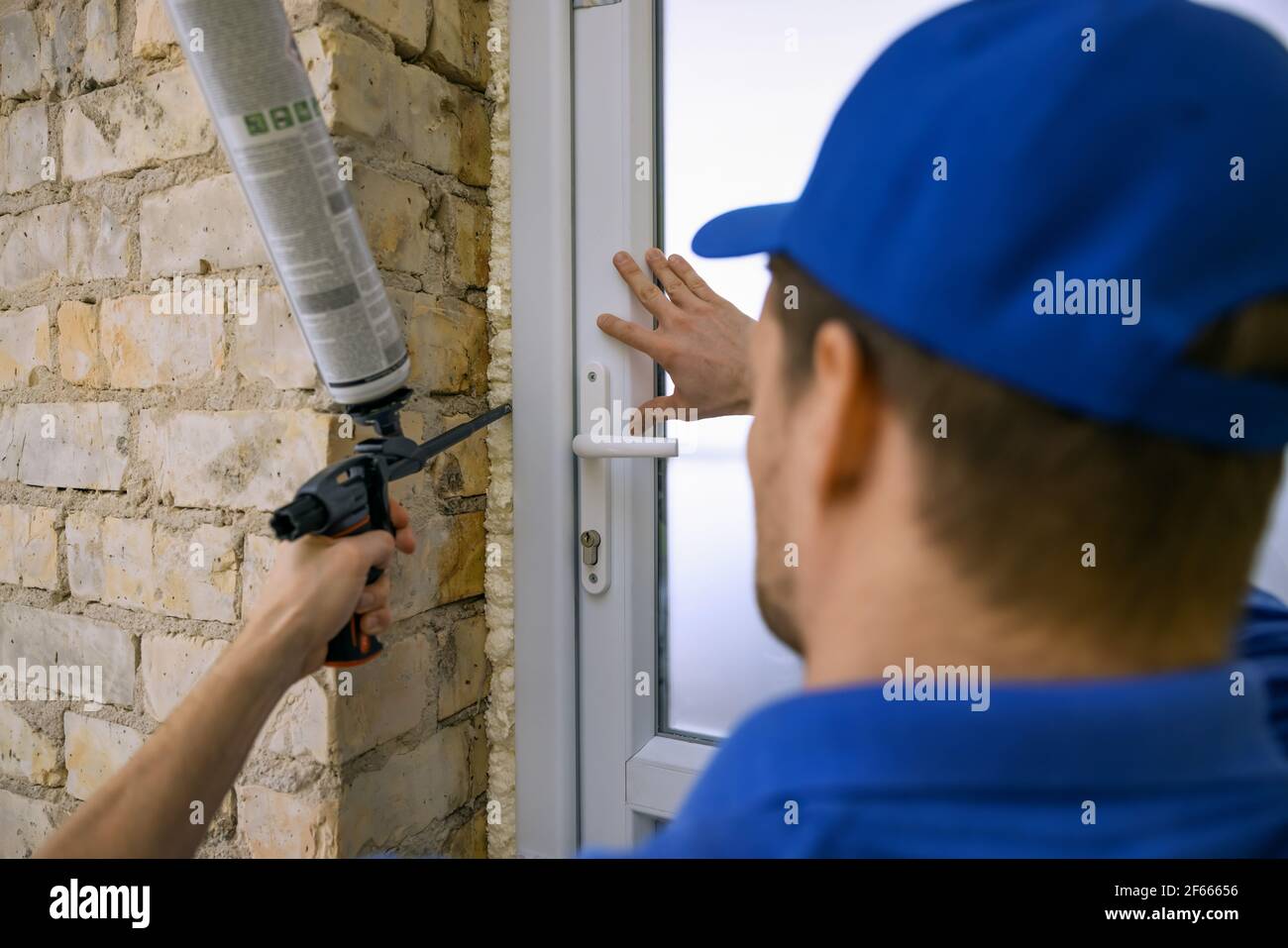 ouvrier installant une nouvelle porte en plastique pvc. montage du cadre avec de la mousse de polyuréthane Banque D'Images