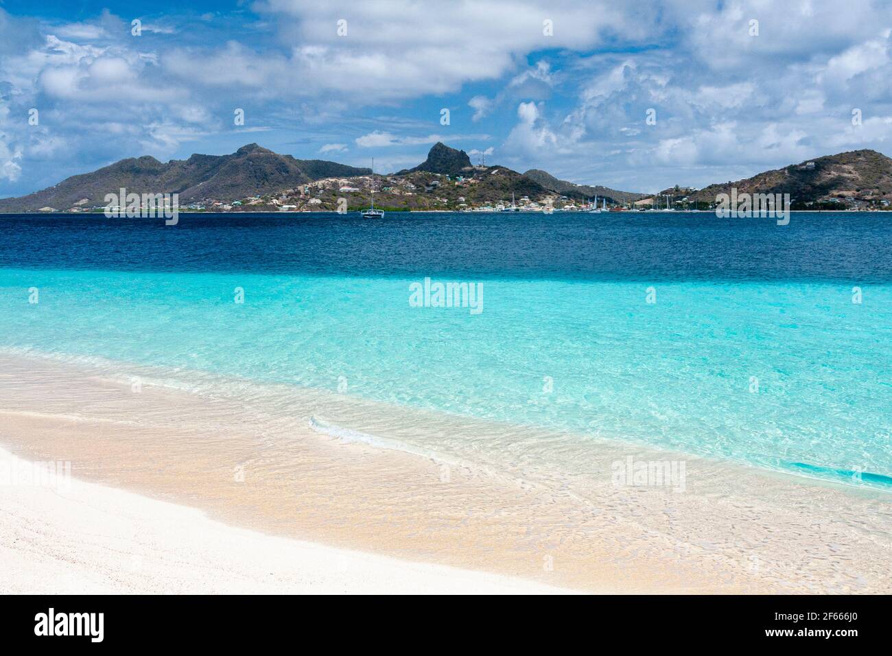 Palm Island Waters Edge-vue sur une plage tranquille avec la mer Turquoise des Caraïbes, les vagues douces et vue sur Union Island avec le ciel bleu. Palm Island, Banque D'Images